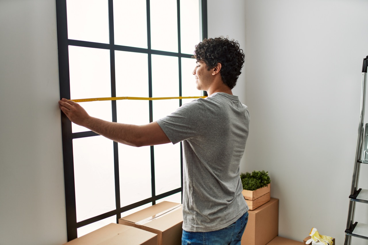 man smiling measuring window for blinds