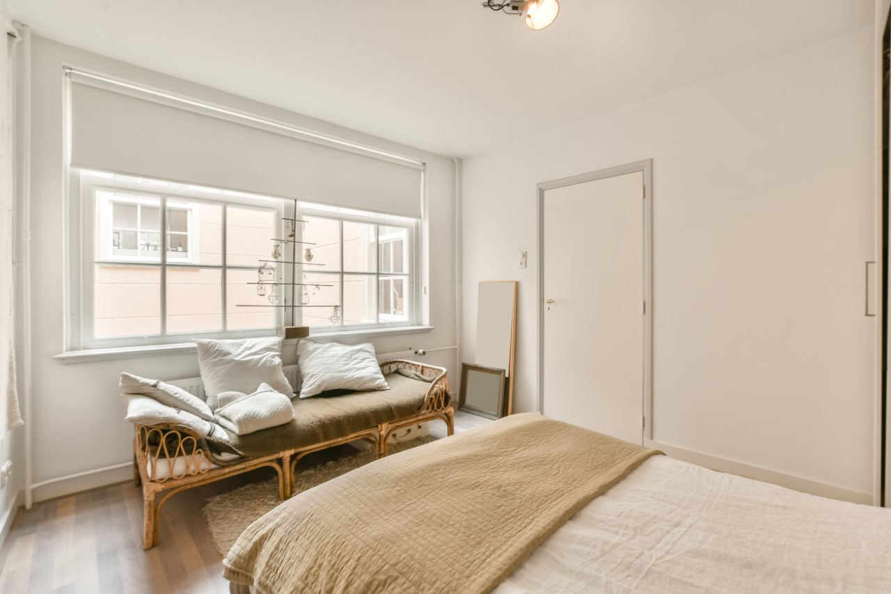 bedroom with double bed and a couch beside a window with blinds